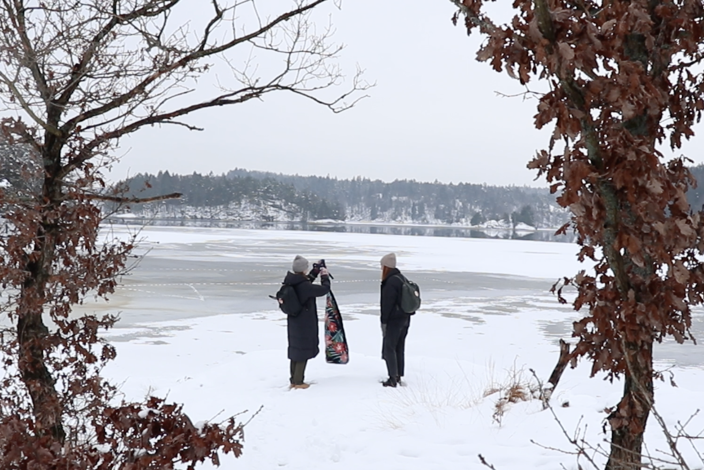 Två tjejer lägger ut en filt vid en snötäckt sjö