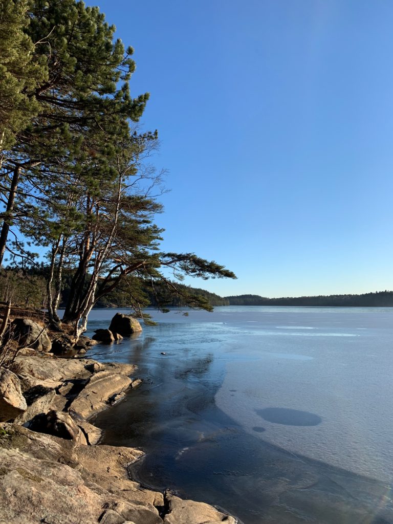 soliga klippor vid en frusen sjö och blå himmel